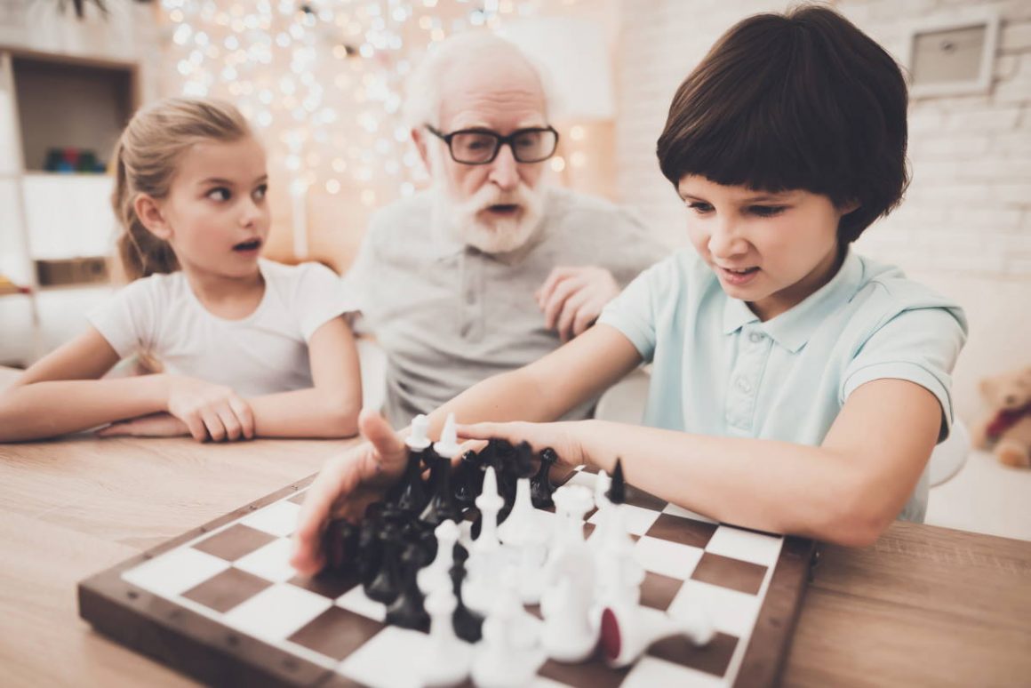 Дед с внуком играют в шашки. Дедушки играют в шахматы. Дедушка и внук играют в шахматы дома. Семья играет в шахматы. Играют в шахматы дед учит внука.